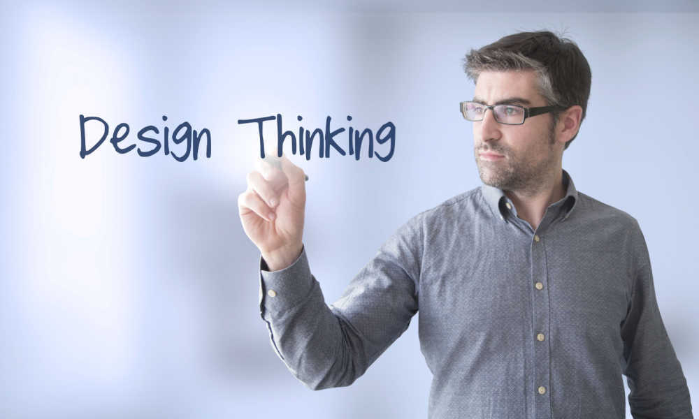 A conceptual image of a businessman writing the words “design thinking.”