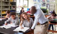 A male high school teacher helps his students understand a complex topic