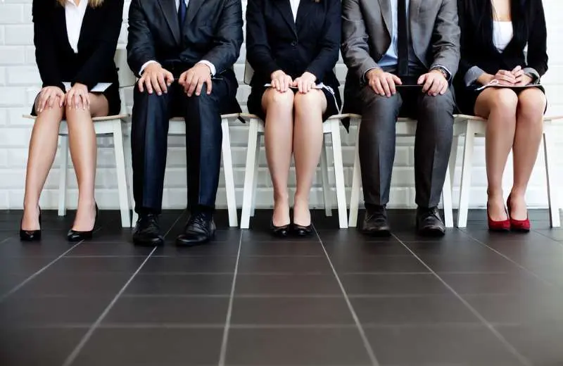 A closeup of interviewees in professional attire sitting in chairs.
