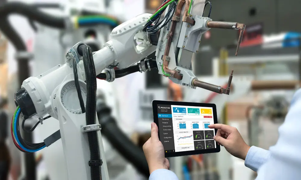 A closeup of hands holding a tablet in front of a robotics instrument.
