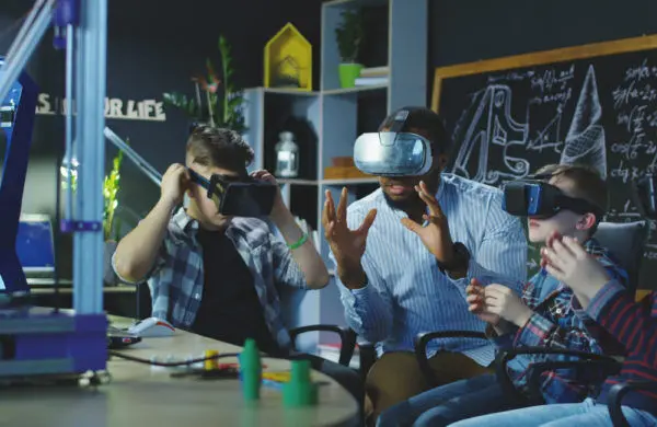 A teacher and several students wear VR headsets in a technology classroom.