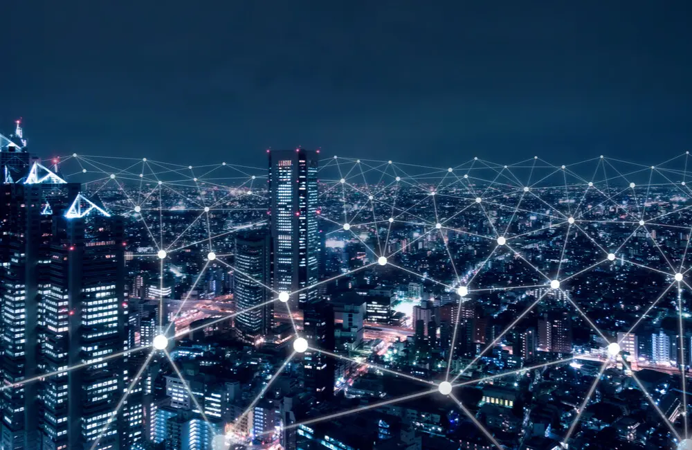 A city skyline with a digital network of connected dots over it.