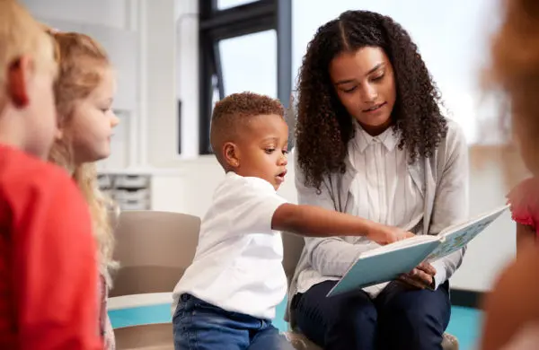 A teacher reads a book to a classroom of young children.