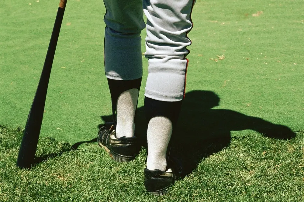 A closeup of a baseball player's cleats and bat.