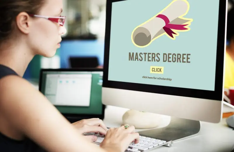 Person at computer with 'MASTERS DEGREE' on screen, seeking online education.