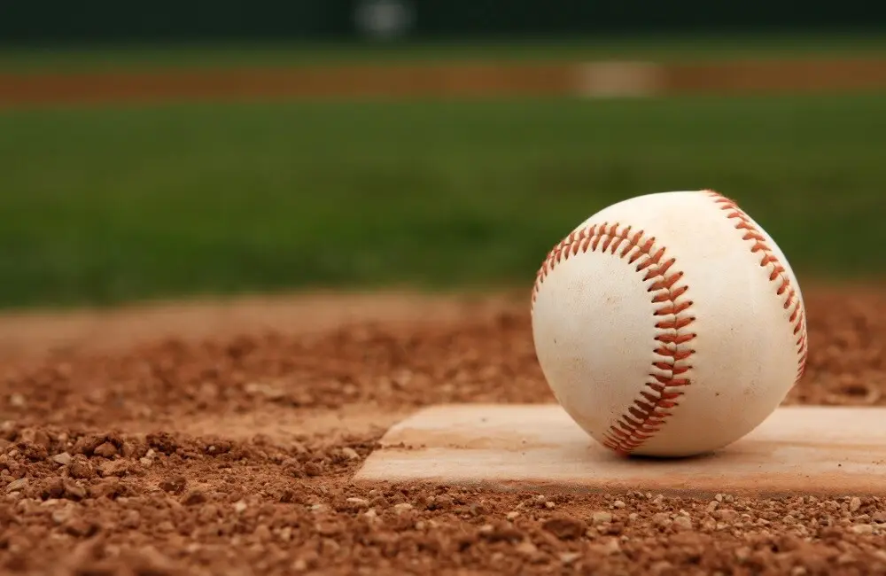 A closeup of a baseball resting on homeplate.