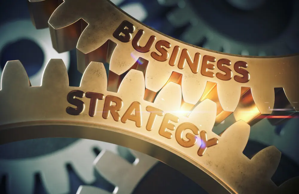 Two interlocked gold gears, one with the word "Business" and the other with the word "Strategy" imprinted.