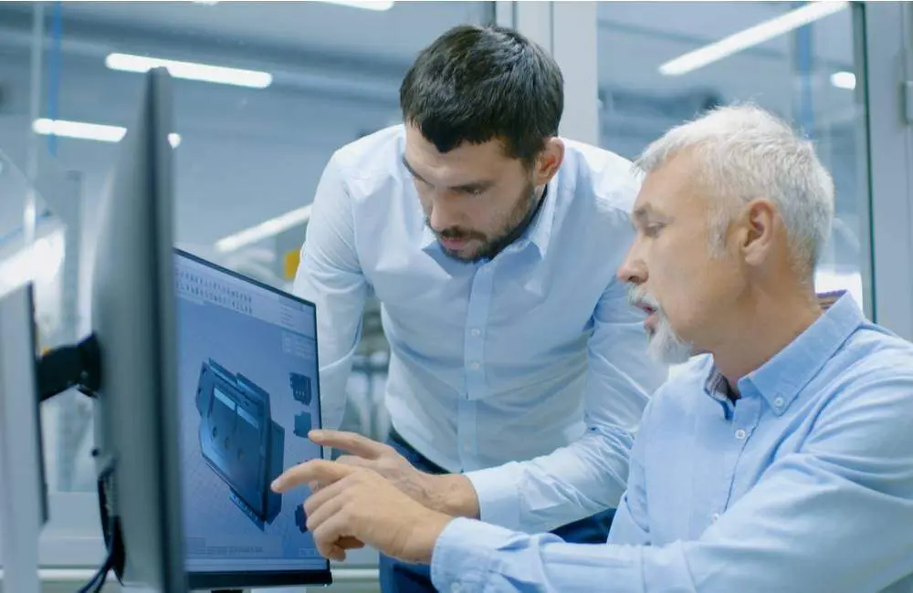 Two product managers study a product design on a computer screen.